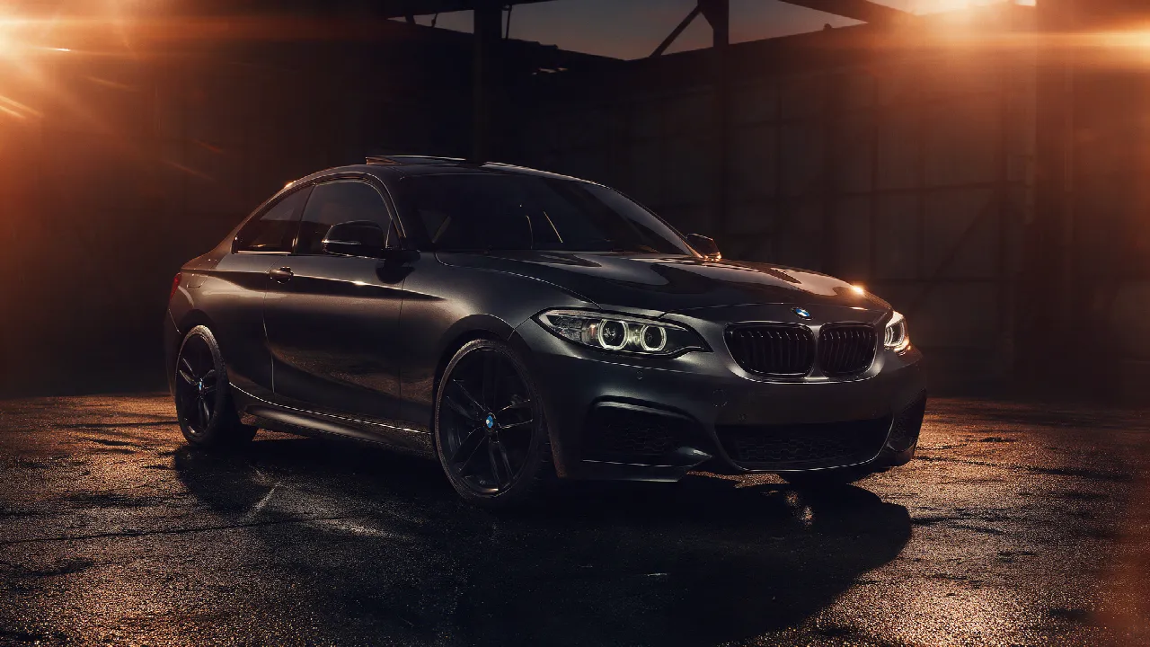BMW 220i Coupé in een donkere werkplaats bij schemering met oranje licht